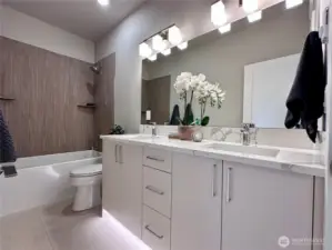 Guest bathroom with dual vanity, and custom tiled shower walls.