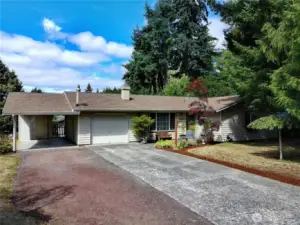 concrete drive to single car garage gravel to carport with storage area in back.