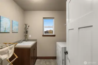 Upstairs laundry room with a large, deep sink. The washer and dryer are included with the home.