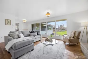 The living room has beautiful oak floors, and is very spacious with a south-facing window wall that looks out to the level rear yard and garden areas, while the natural sunlight streams inside!