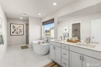 Luxurious primary ensuite bathroom featuring a freestanding soaking tub, dual sink vanity with quartz countertops, tile flooring, and walk-in closet access. Photos are representative only and may display different color package and/or upgrades.