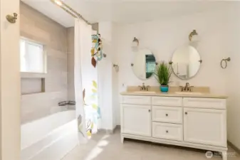 Full primary bathroom with dual sinks and beautiful tiled floor and tub surround