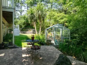 Backyard has a terraced patio and greenhouse with electricity. Notice back yard staircase.