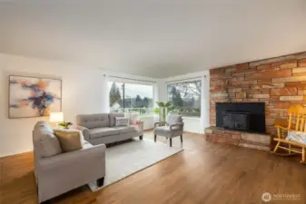 Spacious, open living room with hardwood flooring and spectacular masonry. Large picture windows bathe the room in light. Wood burning insert makes for cozy winters. (staged)
