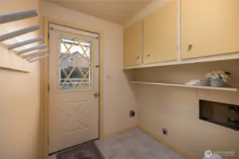 Back door enters into the laundry room with storage and shelving.