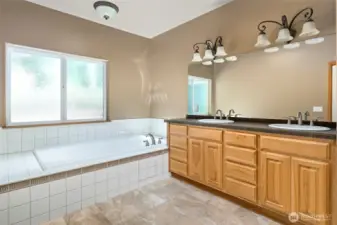Roomy primary bathroom with double vanity and tub.