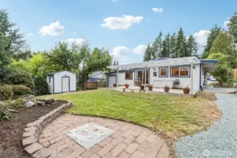 Refreshed backyard with custom brick patio, water feature and raised flower beds.
