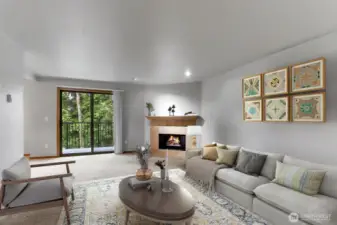 Living room with cozy corner fireplace and tree lined views. This room is virtually staged.