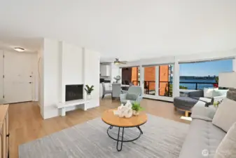 Spacious living area with a cozy fireplace, private balcony access, and walls of windows overlooking Lake Washington.