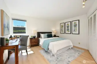 Bright and expansive primary bedroom with space for a desk or sitting area, designed for both relaxation and functionality.