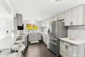 Bright, fully remodeled kitchen at 4612 N 21st St, Tacoma, WA — featuring sleek stainless steel appliances, quartz countertops, modern shaker cabinets, expansive storage, and a stylish herringbone tile backsplash. Large window provides natural light and backyard views. This North Tacoma home offers a contemporary, move-in-ready kitchen designed for cooking, entertaining, and everyday convenience.