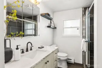 Updated bathroom at 4612 N 21st St, Tacoma, WA — featuring a marble-style vanity countertop, modern black fixtures, mirrored storage cabinets, floating shelves, and a beautifully tiled walk-in shower with glass door. This North Tacoma home offers a clean, contemporary bathroom design with quality finishes and natural light.