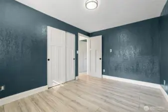 Bright and updated bedroom at 4612 N 21st St, Tacoma, WA — featuring wide-plank wood-look flooring, rich modern wall color, white paneled closet doors, and contemporary lighting. This versatile North Tacoma room offers a clean, refreshed space ideal for a bedroom, guest room, or home office.
