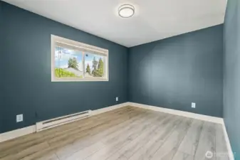 Freshly updated bedroom at 4612 N 21st St, Tacoma, WA — featuring wide-plank wood-look flooring, modern paint tones, crisp white trim, and ample natural light from the adjacent hallway. This versatile North Tacoma room is perfect for use as a bedroom, home office, nursery, or creative space.