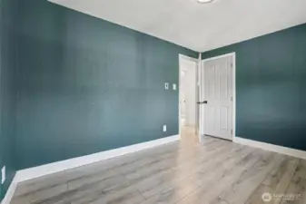 Freshly updated bedroom at 4612 N 21st St, Tacoma, WA — featuring wide-plank wood-look flooring, modern paint tones, crisp white trim, and ample natural light from the adjacent hallway. This versatile North Tacoma room is perfect for use as a bedroom, home office, nursery, or creative space.