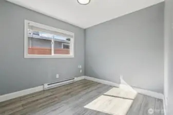Light and bright bedroom at 4612 N 21st St, Tacoma, WA — featuring wide-plank wood-look flooring, soft neutral paint, large window for natural light, and clean white trim. This versatile North Tacoma room is ideal for a bedroom, home office, or guest space with a fresh, modern feel.
