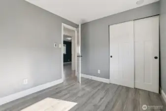 Updated bedroom at 4612 N 21st St, Tacoma, WA — featuring modern gray paint, wide-plank wood-look flooring, white paneled closet doors, and clean trim. This North Tacoma home offers a refreshed, move-in-ready bedroom ideal for sleeping, working from home, or versatile use.