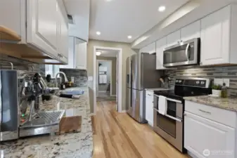 Refreshed kitchen with granite counters, full tile backsplash, and SS appliances.