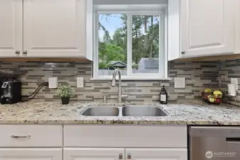 Kitchen window overlooks backyard.