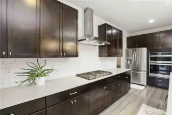 Gas range, subway tile backsplash, overhead fan hood.