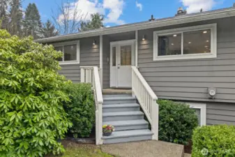 Inviting front entry with covered stair approach, manicured shrubs, and welcoming curb appeal.