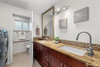 Updated bathroom with dual-sink vanity, generous counter space, and adjacent laundry area for added convenience.