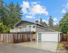 Exterior of the home showing expansive deck, attached garage, and large fenced lot with room to play and entertain.