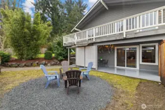 Entertaining area with gravel fire pit space, covered patio access, and private fully fenced yard.