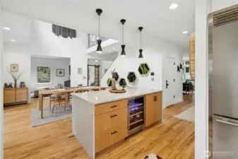 The oversized island anchors the open-concept main level with waterfall-style stone, warm wood cabinetry, statement pendants, and a built-in beverage fridge. With easy flow to dining and living areas, it’s a natural hub for entertaining, après-ride snacks, and everyday gathering.