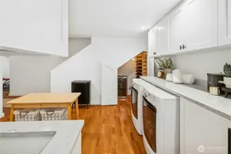 The lower-level laundry room is beautifully finished with generous cabinetry, expansive countertops, and plenty of workspace for sorting and storage. A tucked-away wine storage area adds a thoughtful touch. Perfect for keeping bottles organized and at the ready for entertaining.