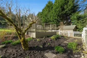 The garden area is thoughtfully laid out with established plantings, pathways, and an enclosed bed space for easy seasonal growing. An irrigation system on a timer supports low-maintenance care, making it easy to cultivate fresh produce and flowers in a private, country setting.