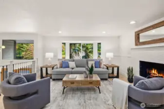Bright and elegant living room with fresh finishes, a cozy wood burning fireplace, and picture windows framing lush greenery. A perfect blend of comfort and style for everyday living or entertaining.