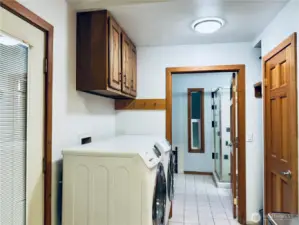View from doorway into laundry area with closet/pantry, bathroom beyond, tile