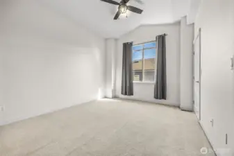 Primary bedroom with vaulted ceilings and ceiling fan