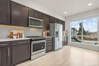 Contemporary kitchen with stainless steel appliances, quartz countertops, and full-height tile backsplash.
