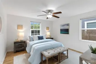 Main floor primary bedroom with hardwood oak flooring and windows facing east and south, fresh paint.