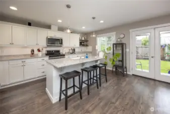 Sunny remodeled kitchen with counter space/cabinet galore, quartz countertops, stainless steel appliance and island with breakfast bar seating.