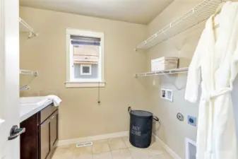Convenient upper-level laundry with utility sink, cabinets, and shelving.