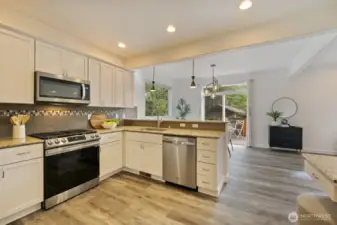 Modern kitchen has a newer stove and breakfast bar, matching LVP throughout home!