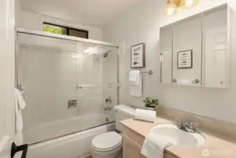 The full hall bath features newly refinished hardwood floors and a mirrored medicine cabinet.