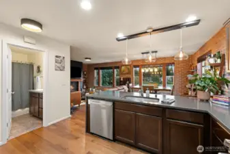Thoughtful design meets everyday convenience in this open-concept living space. Just off the kitchen, a full bathroom with generous storage adds versatility for guests or main-level living, while a walk-in pantry offers plenty of room to keep essentials organized. Rich wood flooring and architectural brick-style wall finishes add warmth and texture, while expansive windows overlooking the lake create a sophisticated backdrop for daily life and entertaining alike.