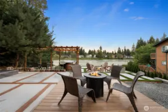 Expansive lakeside patio with composite decking and modern concrete design, perfect for evening fires, morning coffee, or sunset gatherings with friends.