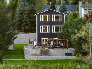 View from the lake back to the home showcasing the scale of the yard, tiered landscaping, and thoughtful design that maximizes both beauty and function.