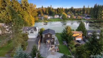 Wide aerial showing the home’s prime position on the lake and its proximity to nearby amenities — lake life with everyday convenience.