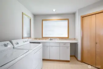 Huge utility room with big storage closet, counters, cupboards, and sink.