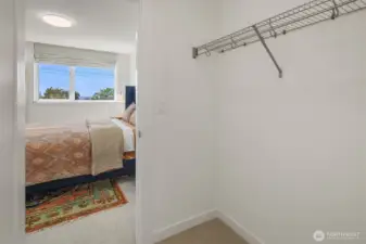Walk-in closet flowing into primary bedroom.