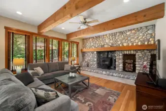 Focal point of living space is the river rock wall with wood burning stove. This keeps home warm and cozy.  Wood wrapped beams, vaulted ceilings make this such an inviting space to relax.