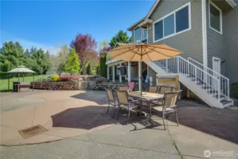 The stairs lead down to an expansive area of hardscaping including this patio. The door situated to the right of the stairs provides access to exceptional storage beneath the home.