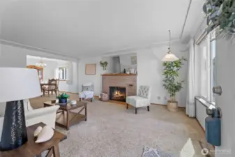 This spacious living room with a wood fireplace has original hardwood floors under the carpet