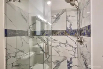 Primary bath includes a walk-in shower with a beautifully designed custom door.